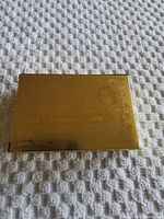 Closed gold-colored box with Canadian $1000 bill design on front embossed in gold