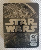 Front side of the black and silver Star Wars 40th Anniversary tin showing the Star Wars logo and a schematic design background.