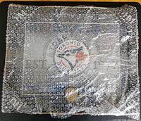 The original packaging showing the art sign wrapped in branded bubble wrap with Toronto Blue Jays logo and Highland Mint logo markings.