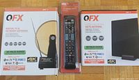 Two QFX digital TV antennas in original packaging and a QFX universal remote control in blister pack