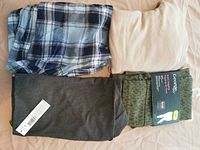 Four folded clothing items: blue checkered shorts, brown shorts, gray tights, black spandex shorts with green print waistband
