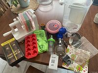 Full overview of all kitchen items included in the lot laid out on a wooden table.