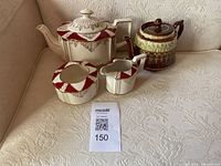 Image showing bone china tea set with teapot, sugar bowl, milk jug, and additional teapot on a cream sofa.