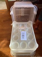 Large plastic cupcake holder with clear lid open showing one tier of tray with 12 slots.