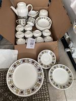 Photo shows the entire dishware set inside a cardboard box with some pieces arranged outside the box for clear view