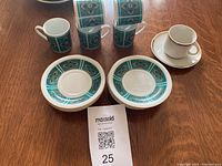 Photo showing 4 teal blue and gold design espresso cups and 4 matching saucers, plus one white cup and saucer with gold trim.