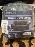 Photo of packaged H.VERSAILTEX Premium Stretch Slipcover labeled as 3 piece for loveseat with branding and product image