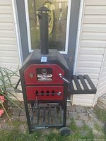Full front view of pizza oven and grill showing red doors and chimney on top
