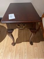 Top and front view of a wooden side table with decorative cabriole legs and ornate drawer pull.