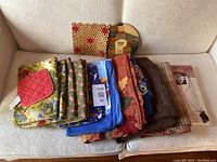 Lot of various folded tablecloths and placemats arranged on a couch, showing multiple colors and patterns
