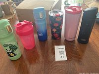 Photo showing all six travel mugs and thermoses lined up on table.