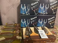 Four boxes of crystal goblets and two boxes of glass goblets on a patterned tablecloth.