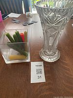 Photo showing the crystal vase and candles in a square container with a lot number card.