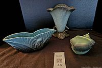 Three pottery pieces including Hull marked vase, blue-green shell shaped piece, and small lidded container