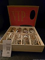 Box with eight highball glasses inside showing architectural and statue designs in gold and white.