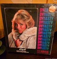 Front view of sealed puzzle box showing Krystle Carrington in fur coat with repeated Dynasty text and price sticker.