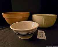 Three bowls together including yelloware, Hall China with blue floral pattern, and Hull pottery with blue band