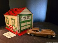 Side view of lithographed tin garage and toy Jaguar car showing the automatic door and roof detail.