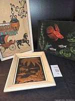Three framed art pieces: embossed copper tropical scene, string art fish, gravel art horse and carriage.