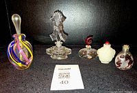 Full set of five perfume bottles showing various styles, colors, and sizes on a black background.