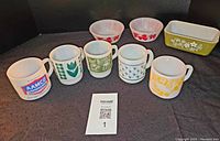 Overview photo showing 5 mugs, 2 bowls and 1 rectangular dish with various graphic designs in white glassware