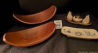 Teak nesting platters, California ceramic dish and Carlton Ware condiment set on a black cloth background