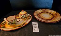Photo showing entire lot with two platters, sugar bowl with lid, creamer, and oval serving tray on display with a MaxSold lot number card.
