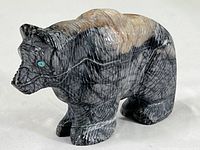 Front left side view of the hand carved stone bear figurine showing visible texture and natural color patterns
