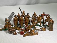 Full set of 20 metal toy soldiers arranged on white background showing variety of poses and weaponry.