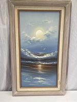 Full view of the framed vertical seascape painting showing waves, seabirds, and a glowing sun or moon with clouds.