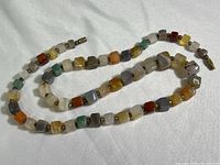 Full length view of polished stone necklace displaying multicolored cube-shaped beads.