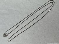 Full view of the sterling silver chain necklace laid out flat on a neutral fabric surface.