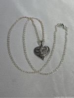Full view of the sterling silver heart pendant on the chain against a plain background, showing the chain looped loosely.