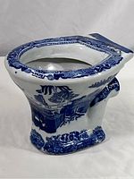 Side angle showing the blue and white ornate design on the ironstone toilet bowl shaped miniature sample.