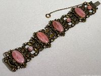 Full view of the vintage Victorian bracelet showing four large pink opaline oval stones, small round pink opaline beads, ornate metal details, and safety chain clasp.