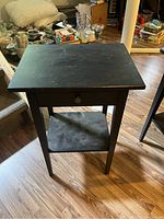 Black IKEA HEMNES nightstand top surface visible showing extensive scratching and wear.