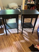 Two IKEA HEMNES black nightstands side by side on wood flooring showing structural condition and overall appearance.