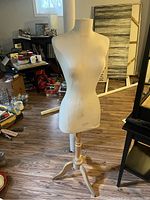 Front view of 54 inch fabric-covered mannequin torso on wooden stand, showing discoloration and stains on fabric with surrounding room details.