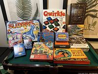 Full view of lot on pool table showing all 11 games and puzzles including Sorry Sliders, Qwirkle, Sherlock Holmes Puzzle Collection, and others.