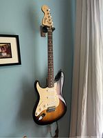 Full front view of left-handed Squier Stratocaster guitar hung on wall mount