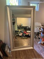 Full length mirror showing entire piece with clear mirror and silver frame, some signs of wear visible.