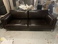 Front view of the tobacco brown faux leather IKEA couch showing indentations and condition of upholstery.