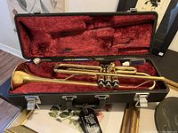 Brass trumpet inside open case showing instrument layout and accessories