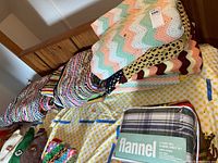 Knit blankets in different colors and patterns stacked on a bed