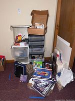 View of the full lot showing plastic storage drawers, stack of craft books/papers, and boxed kits on floor and on top.