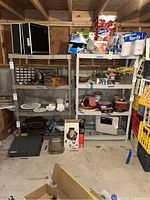Wide view of plastic shelving units with assorted kitchenware, tools, and household items stored on shelves in basement.