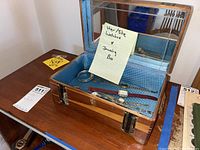 Jewelry box open showing 5 wristwatches and one bracelet inside on blue fabric lining with mirror in lid.