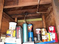 Photo of soldering gas cylinders, wire spools and cans of soldering supplies on wooden shelving