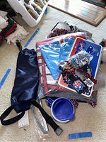 Photo of folded Patriots and American flag blankets, beaded NFL necklaces, plastic license plate holders and navy blue handwarmer pouch.