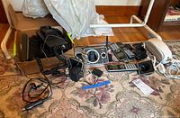 Photo showing multiple telephones, charging stands, power adapters, and accessories arranged on a patterned rug in front of a wooden baseboard.
